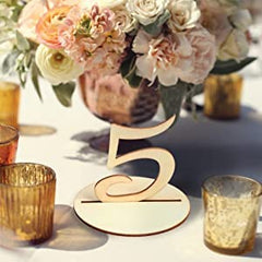 Wooden table number '5' on a decorative floral arrangement with candles in the background