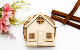 Wooden house model with flowers and cinnamon sticks on a white background