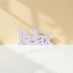 White 'Relax' sign on a white surface with a beige background
