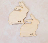 Two wooden rabbit shapes on a light pink background