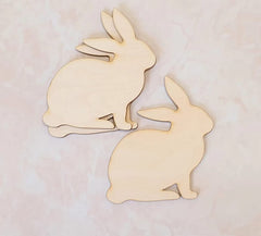 Two wooden rabbit shapes on a light pink background