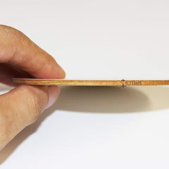 Hand holding a thin wooden strip with measurement label on a white background