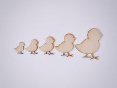Five wooden cutout shapes of chicks on a white background