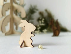 Wooden rabbit figurine on a white surface with decorative elements in the background