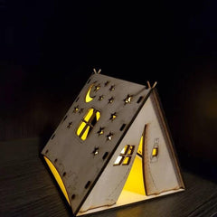 Wooden house-shaped lamp with cut-out windows and door on a dark background