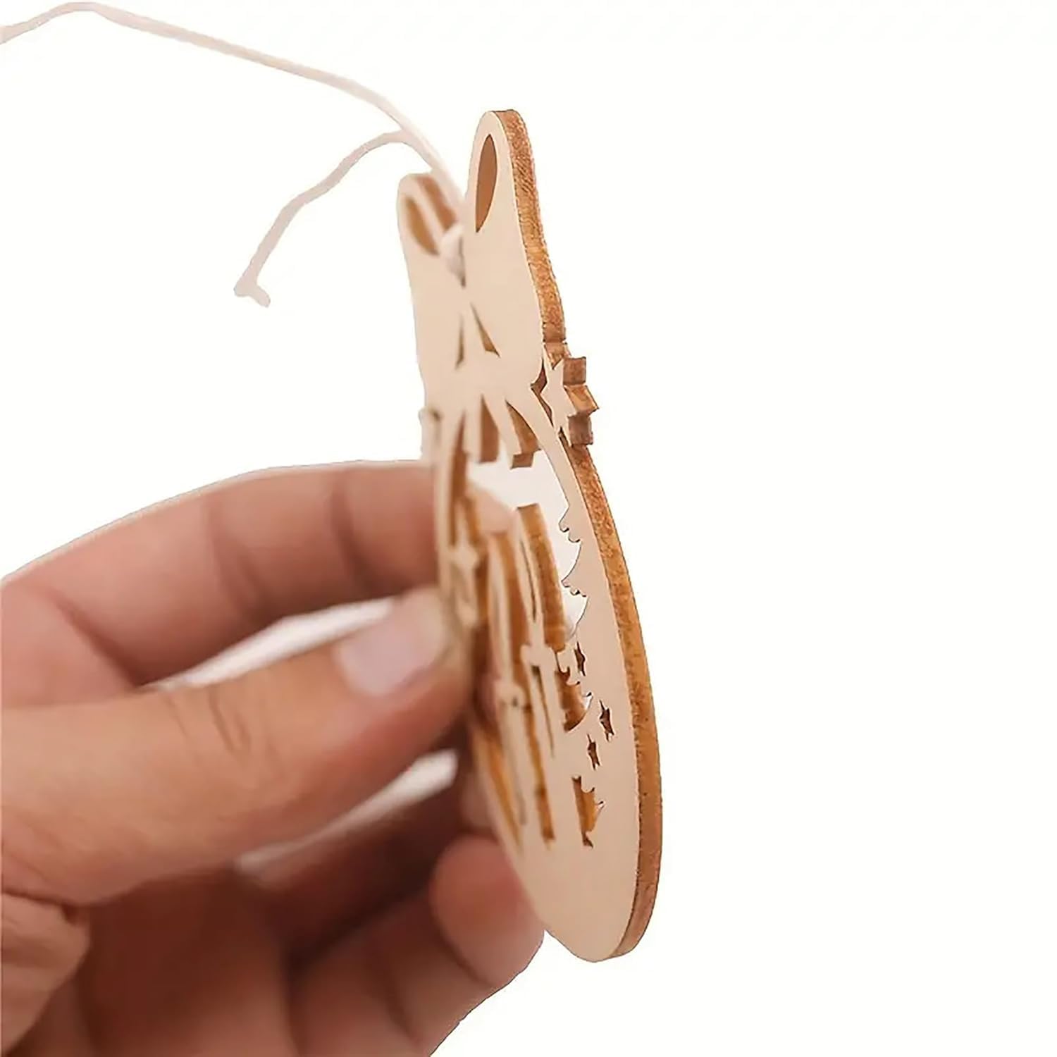 Hand holding a wooden ornament with cut-out design on a white background