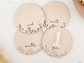Wooden discs with milestone markings for baby's development on a light background