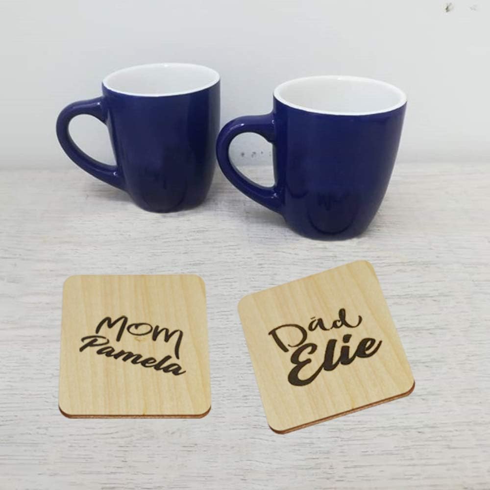 Two blue mugs with wooden coasters labeled 'Mom Pamela' and 'Dad Elie' on a light gray surface.