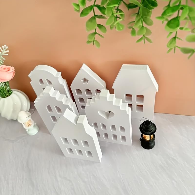 Set of white decorative houses with a candle on a light surface with a beige background