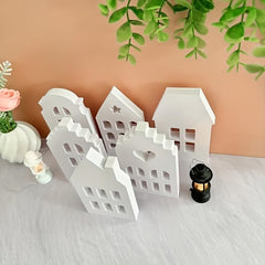 Set of white decorative houses with a candle on a light surface with a beige background