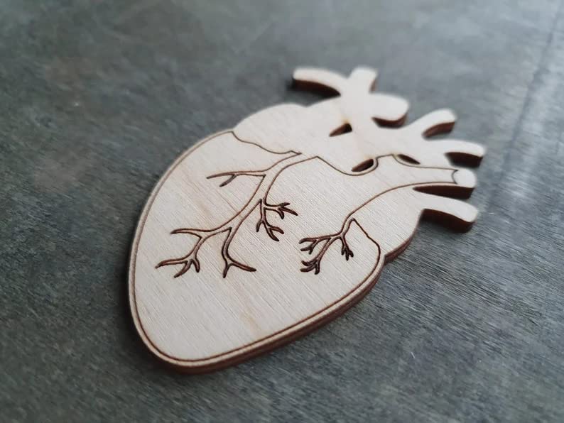 Wooden heart-shaped object with cut-out design on a gray surface