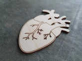 Wooden heart-shaped object with cut-out design on a gray surface
