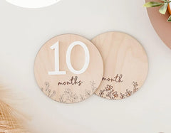 Two wooden circular plates with '10 months' and '9 months' text on a light background.
