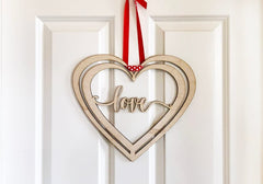 Heart-shaped wooden decoration with 'love' text hanging on a white door.