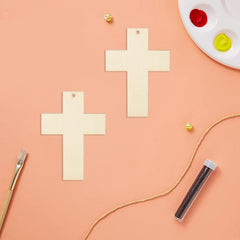 Wooden crosses on a peach-colored surface with paint supplies.