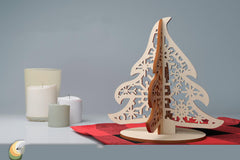 Wooden Christmas tree decoration on a red tablecloth with candles in the background