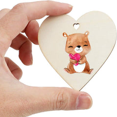 Heart-shaped wooden ornament with a bear holding a pink heart, held by a hand on a white background