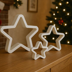 White star-shaped decorations on a wooden surface with a Christmas tree in the background.