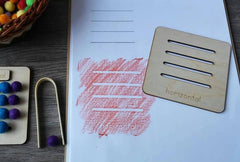 Educational tools including a wooden shape sorter and color sorting board on a table.