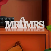 Decorative sign with 'MR & MRS' on a wooden surface with a brown background