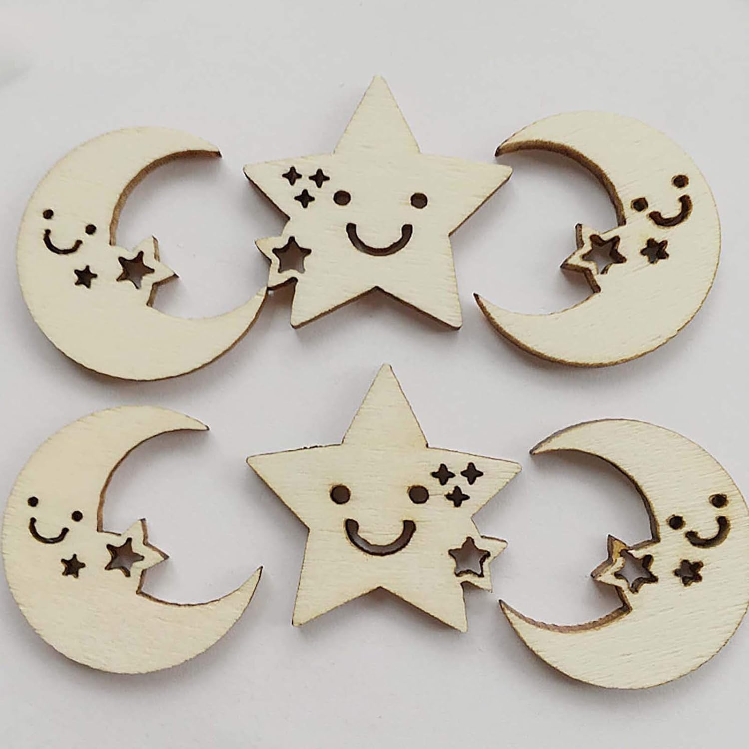 Wooden moon and star decorations with smiling faces on a light gray background