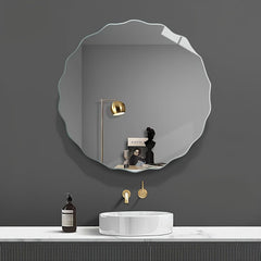 Round mirror on a gray wall above a sink with decorative items.