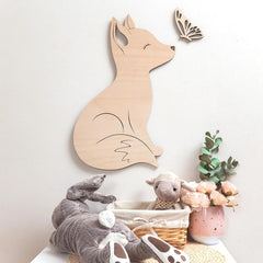Wooden fox wall decoration in a child's room with toys and plants.