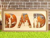 Wooden decorative sign with 'DAD' cutout, featuring images of a father and child, against a brick wall.
