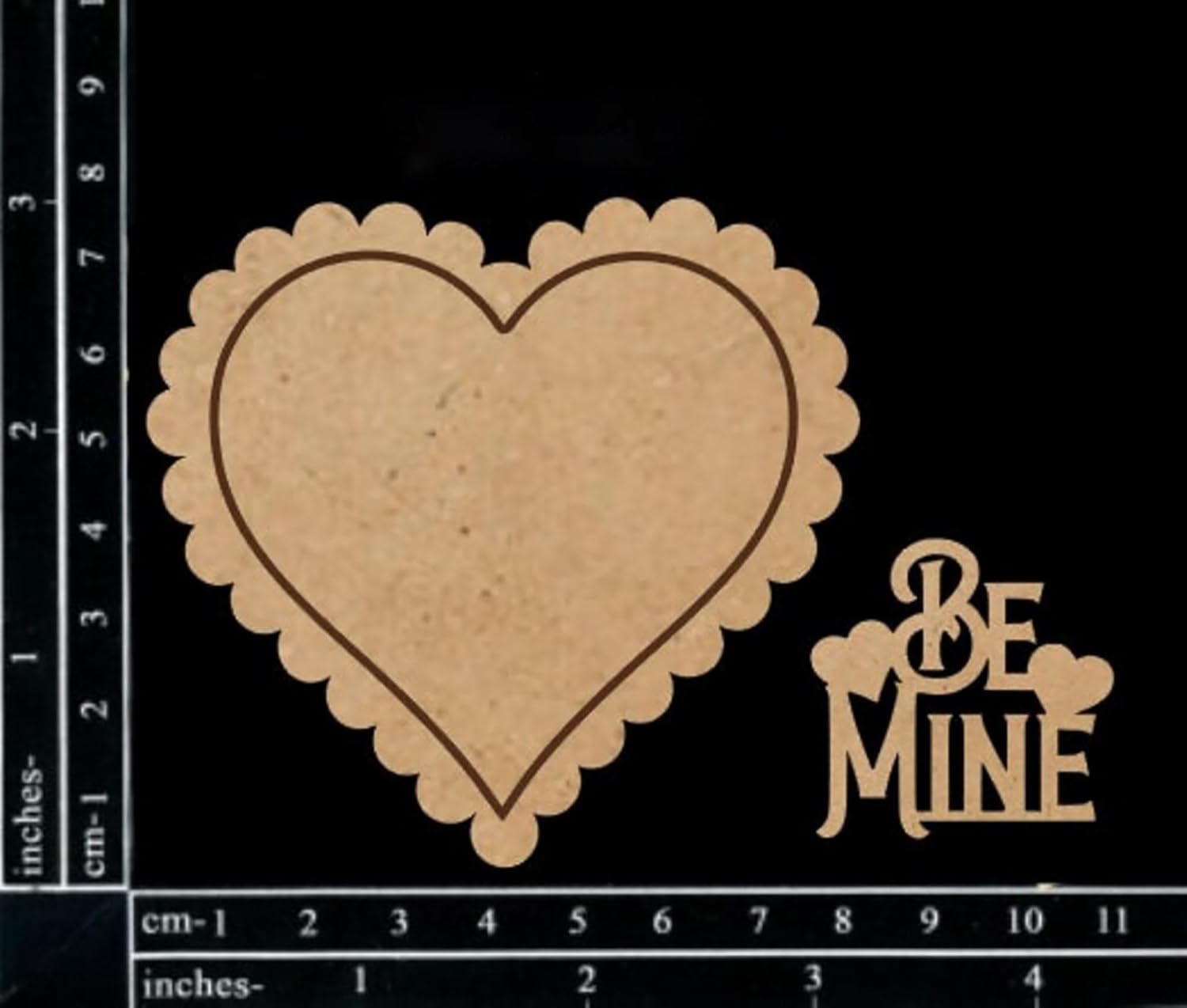 Heart-shaped wooden cutout with 'Be Mine' text on a black background with measurement scale.
