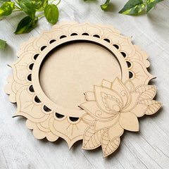Wooden circular decorative item with lotus design on a light wooden surface.