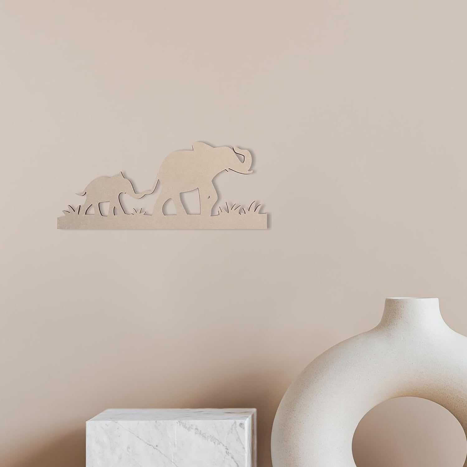 Decorative wall art of elephants on a beige wall with a vase and framed picture in the foreground.