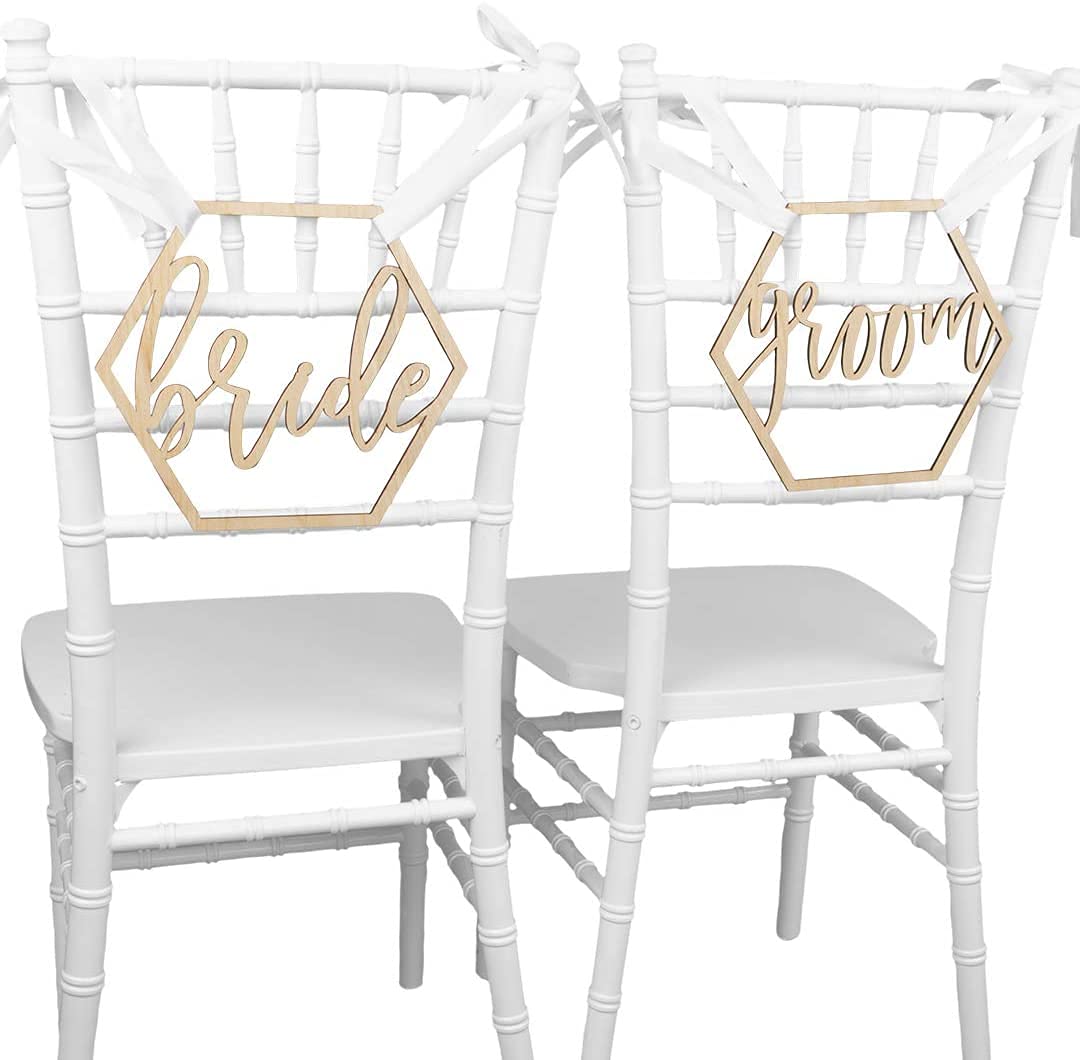 Two white chairs with 'bride' and 'groom' signs on a white background