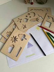 Wooden stencils with geometric shapes on a coloring book page with pencils.