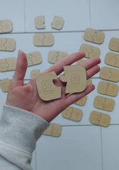 Hand holding wooden letters 'E' with more letters scattered on a light surface