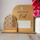 Wooden countdown to Eid and Ramadan Mubarak display with flowers and a candle.