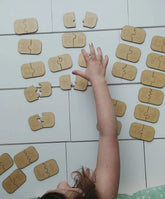 Child's hand reaching for a puzzle piece on a tiled floor with alphabet puzzles.