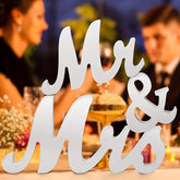 Decorative sign 'Mr & Mrs' with a blurred background of a couple at a table.