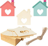 Colorful house-shaped wooden tags with heart cutouts, a box of additional tags, and twine on a white background.