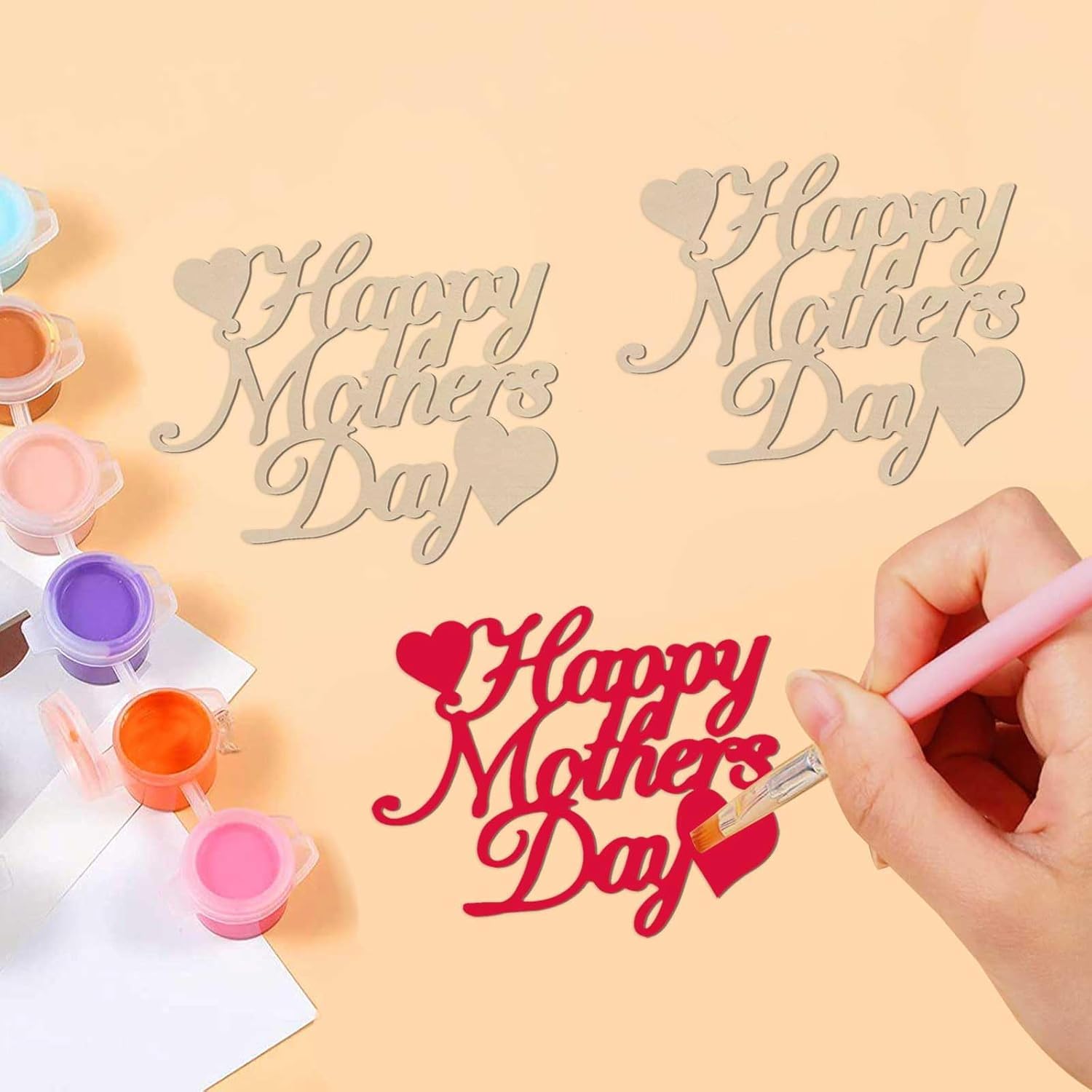 Decorative 'Happy Mother's Day' signs with paint supplies on a peach background