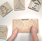 Wooden geometric shapes and a board with circular patterns on a white surface.