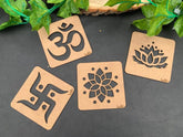 Four wooden coasters with engraved symbols on a dark surface with green leaves.