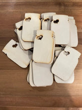 Stack of white rectangular tags with heart cutouts on a wooden surface