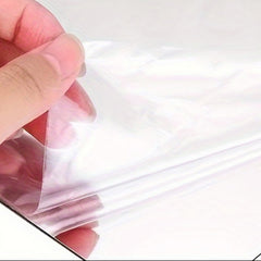 Hand holding a clear plastic sheet against a white background