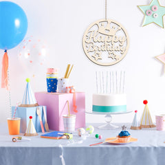 Birthday party setup with cake, balloons, and decorations on a table.