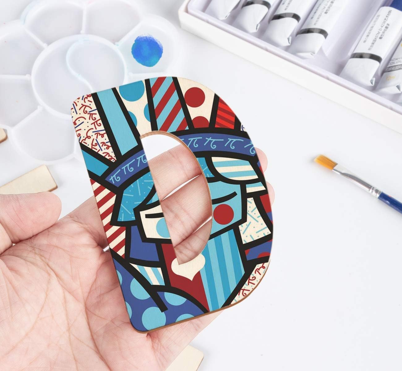 Colorful abstract design on a phone case held by a hand with art supplies in the background