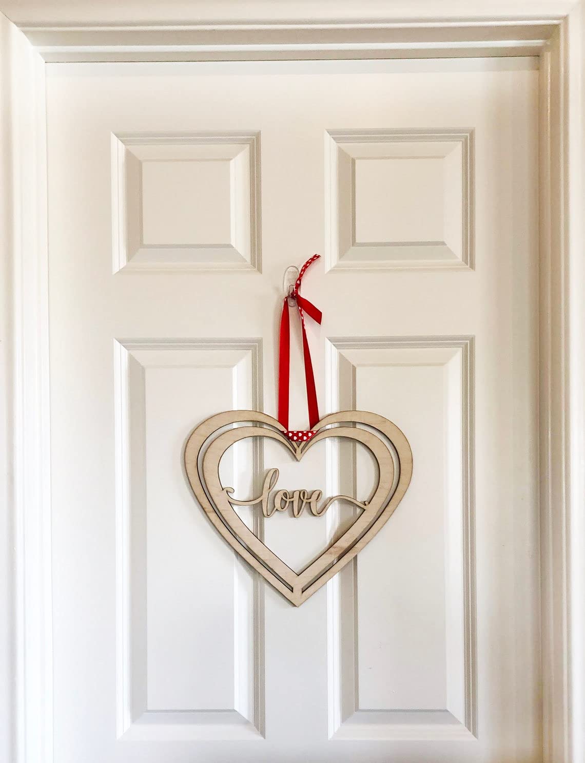 Heart-shaped decorative sign with 'love' on a white door