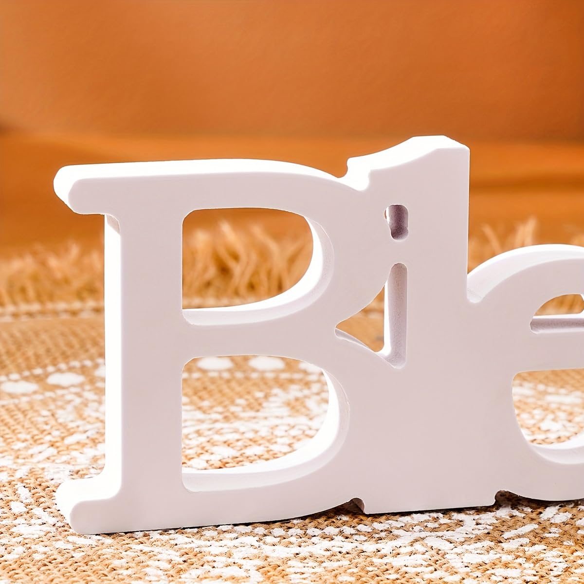 White letter 'B' on a textured surface with an orange background