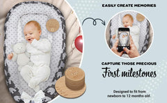Baby in a crib with milestone discs and a phone app for capturing memories.