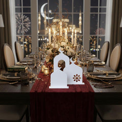 Decorated dining table with white lanterns and candles, set against a window view of fireworks and city lights.