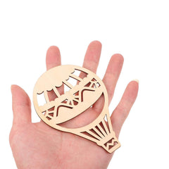 Wooden hot air balloon cutout held in a hand on a white background